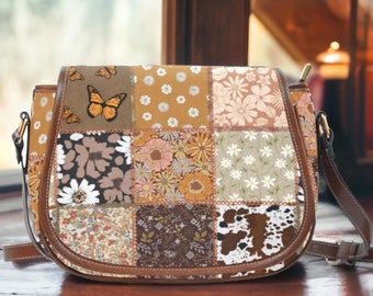 May include: A brown leather patchwork crossbody bag with a floral and butterfly design. The bag has a long adjustable strap and a flap closure.