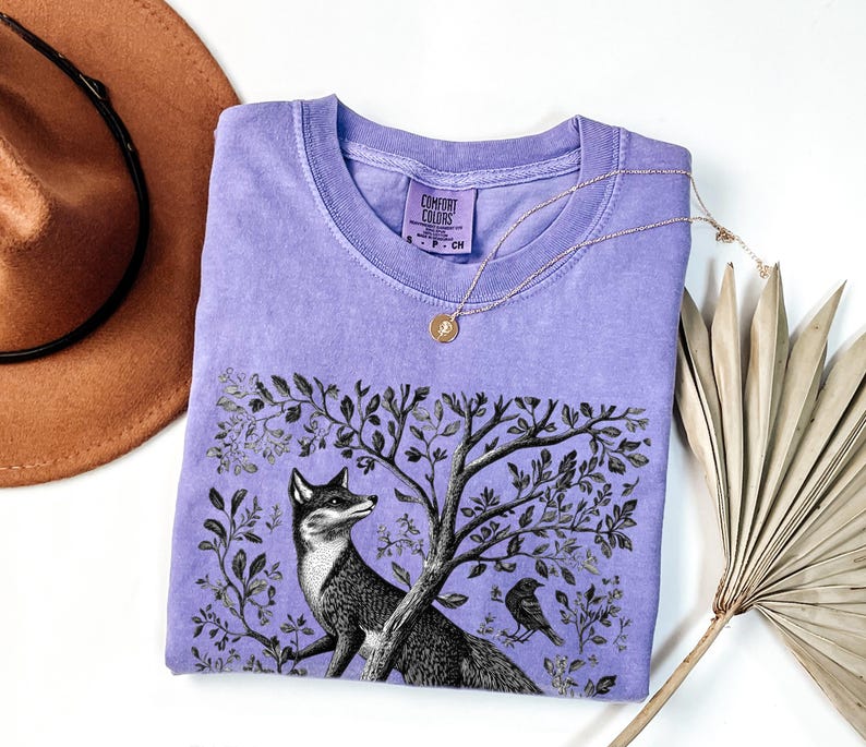 Peut inclure: Un t-shirt lavande avec une illustration en noir et blanc d'un renard dans une sc&egrave;ne de for&ecirc;t. Le t-shirt porte le texte "Comfort Colors" imprim&eacute; sur l'&eacute;tiquette.