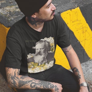 May include: A black t-shirt with a graphic of Johannes Brahms surrounded by white flowers and the text "Brahms" printed on the front.