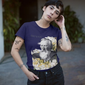 May include: A navy blue t-shirt with a floral design and a portrait of Johannes Brahms. The text "BRAHMS" is printed on the shirt.