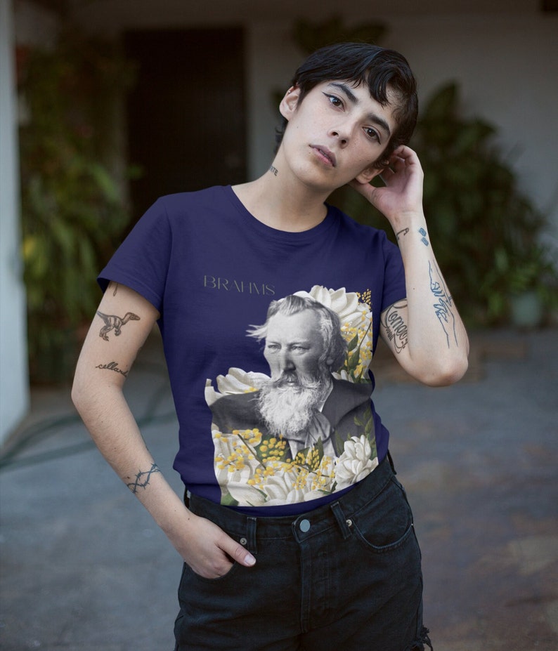 May include: A navy blue t-shirt with a floral design and a portrait of Johannes Brahms. The text "BRAHMS" is printed on the shirt.