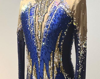 May include: A navy blue and gold leotard with long sleeves, designed for rhythmic gymnastics. The garment features intricate crystal and sequin embellishments, with a sheer nude mesh upper bodice and sleeves. The design includes a high neckline and a skirted bottom.