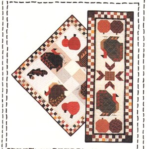 May include: A Country Threads sewing pattern titled Gobbler's Roost #401. The cover features a square quilt and a rectangular table runner, both decorated with patchwork turkeys, pumpkins, and acorns in shades of brown, orange, and cream.