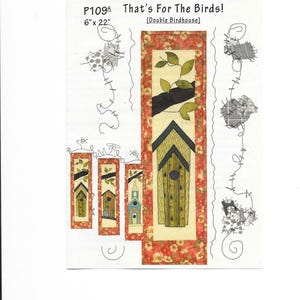 Könnte beinhalten: Stoffpaneel mit dem Text "That's For The Birds!" und "Double Birdhouse". Das Panel zeigt ein großes Vogelhausdesign mit einem floralen Rand und mehreren kleineren Vogelhausdesigns. Das Panel misst 15 cm x 56 cm.