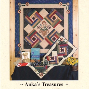 Könnte beinhalten: Ein Quiltmuster mit dem Titel "Freedom Blooms" mit einem Wandquilt und einem Läufer. Der Quilt hat ein zentrales Design mit einer Blumenvase und Sternmustern. Weitere Artikel sind ein Foto, ein Buch, eine Uhr und Blumen.