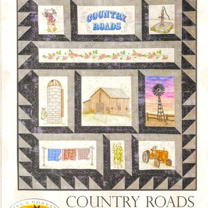 May include: A hand embroidery project titled "Country Roads" featuring a quilt design. The quilt showcases rural scenes: a barn, windmill, tractor, and clothesline. The design includes the text "Country Roads" in blue script.