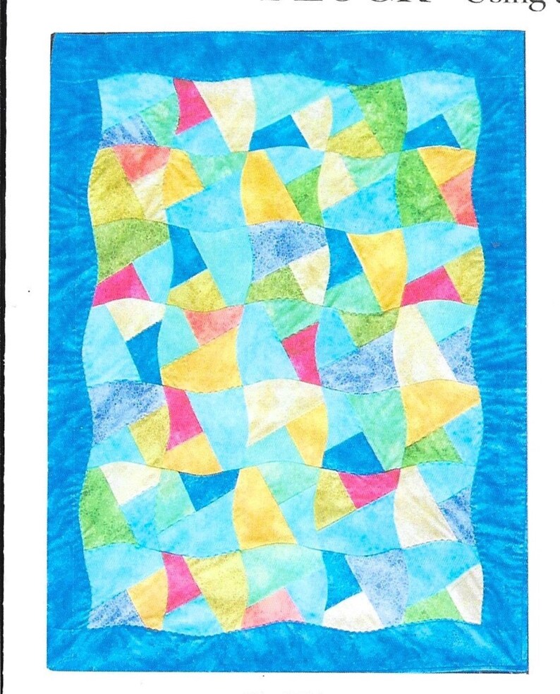 May include: A colorful quilt with a blue border. The quilt features a patchwork design of various shapes in shades of blue, yellow, green, pink, and white. The quilt has a wavy edge and is likely handmade.