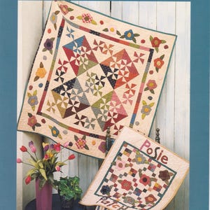 May include: A quilt pattern named "Posie Patch" by Cheri Saffiote. The image displays two quilts, one large and one small, featuring floral and geometric patterns. The larger quilt measures 96.5 x 96.5 cm. The smaller quilt measures 50.8 x 61 cm.