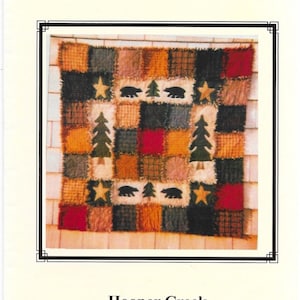 Könnte beinhalten: Ein Patchwork-Quilt mit Waldthema. Der Quilt zeigt Quadrate in verschiedenen Farben, darunter Rot, Schwarz und Beige. Er hat applizierte Bilder von Bären, Bäumen und Sternen. Der Text "Bears 'n Forest" steht oben.