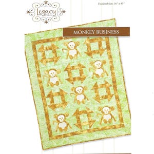 May include: A quilt with a green background and a repeating pattern of gold-colored arrows and monkey figures. The quilt measures 36 x 45 inches. The text "MONKEY BUSINESS" is displayed on a brown banner.