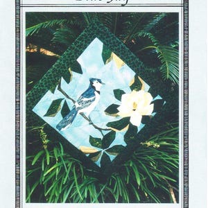 May include: A Blue Jay quilt pattern with a detailed illustration of a blue jay perched on a branch with a white flower. The design is set against a backdrop of lush greenery and includes the text "Blue Jay".