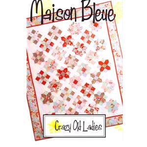 May include: A quilt featuring a repeating pattern of red, pink, and floral fabric squares on a white background, bordered by a floral print. The text "Maison Bleue" appears at the top, and "Crazy Old Ladies" is printed in a box at the bottom.
