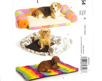 May include: A sewing pattern for dog beds, featuring three different designs. The top bed is a sofa style with a floral print, the middle bed has a floral pattern, and the bottom bed is a tie-dye mat. The text "Easy stitch'n save" is visible.