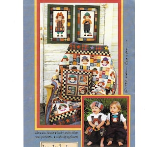 Può includere: Immagine colorata con una trapunta, un cuscino e quadri da parete con personaggi simili a bambole. La trapunta e il cuscino hanno un design patchwork con facce di bambole. Sono mostrati anche due quadri da parete incorniciati e due bambini con abiti a tema bambola.