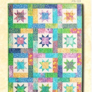 May include: A vibrant quilt showcasing a star pattern. The design incorporates squares in shades of blue, green, yellow, and purple, each with a star motif. The text "LUCKY STARS" and "Fat Quarter Quilt" are displayed on the quilt.