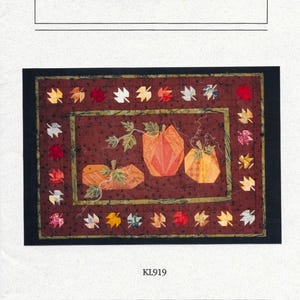 May include: A paper foundation pattern titled "Autumn Fields" featuring a quilted design with three orange pumpkins and colorful leaves. The design is set against a dark red background with a black border. The text "Kris Lange Designs" is also visible.