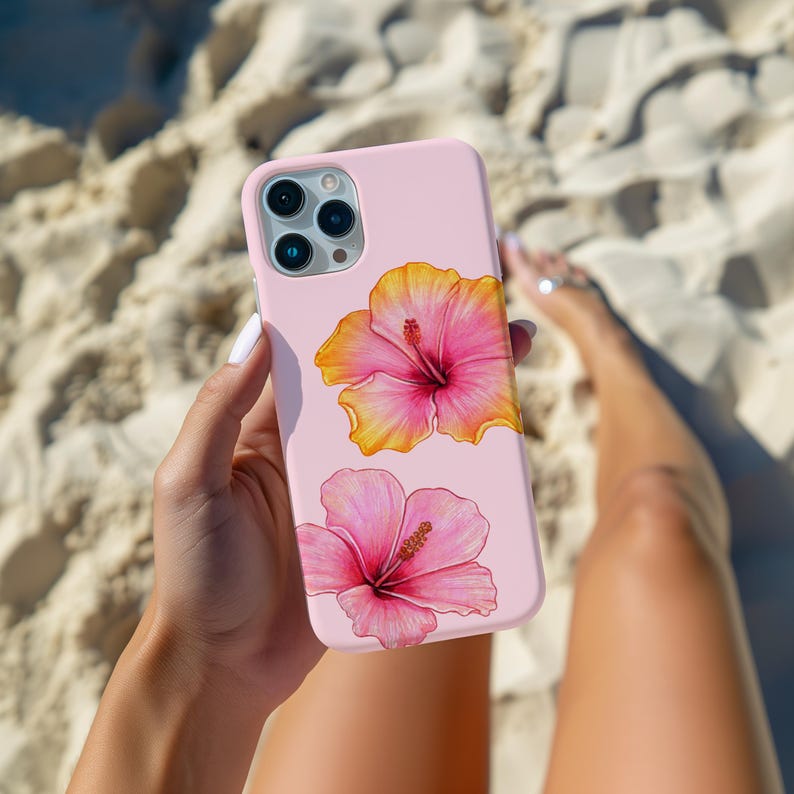 May include: A pink phone case with two hibiscus flowers. The flowers are yellow and pink with a white center. The phone case is made of silicone and has a matte finish.