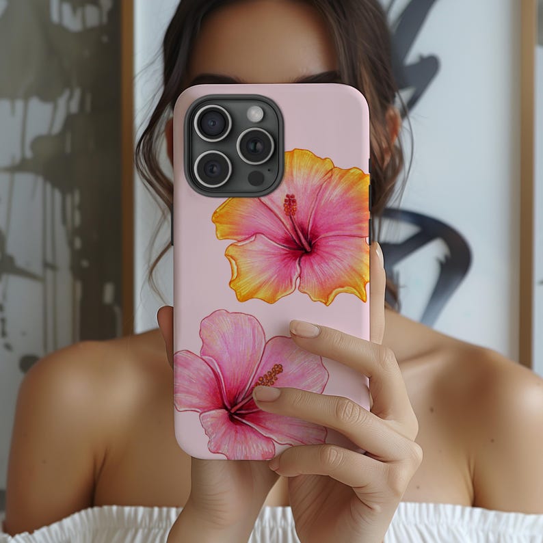 A stylish phone case featuring a pink hibiscus floral design, adding a tropical and summery touch. The case is designed for Apple, Samsung, and Google Pixel devices, offering a slim yet durable build for protection against scratches and minor drops. The vibrant hibiscus flowers stand out beautifully against the soft pink background, making it a perfect accessory for those who love floral aesthetics, island vibes, and elegant designs. Ideal for adding a fresh, tropical feel to any smartphone.