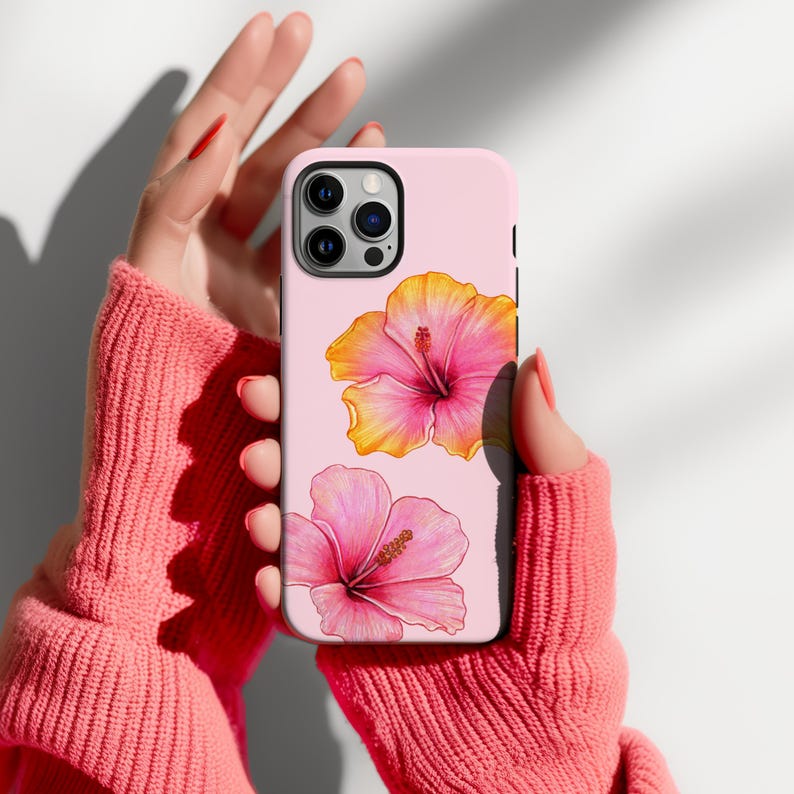 May include: A pink phone case with a floral design. The case features two pink and yellow hibiscus flowers.