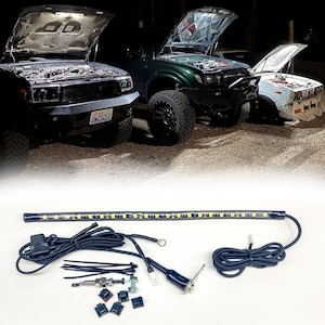 May include: A black LED light strip with a black wire and a black connector. The light strip is about 12 inches long and has a white light. The light strip is on a white surface. There are also some other parts included, such as screws, zip ties, and a connector.