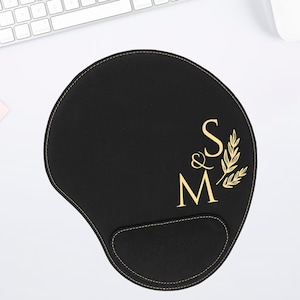 May include: Black mouse pad with a gold embroidered design of the letters "M & S" with a small leaf design.