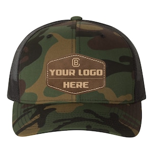 May include: A camouflage trucker hat with a brown leather patch that says "YOUR LOGO HERE" in a tan font.