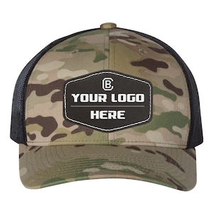 May include: A camouflage trucker hat with a black mesh back. The hat has a black leather patch with white stitching and the text "YOUR LOGO HERE" and a letter "B" inside a circle.