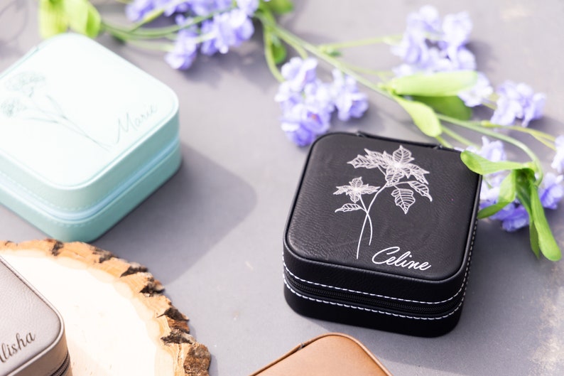 Pu&ograve; includere: Tre piccole scatole quadrate per gioielli con disegni floreali e nomi personalizzati. Le scatole sono di colore azzurro, nero e marrone.
