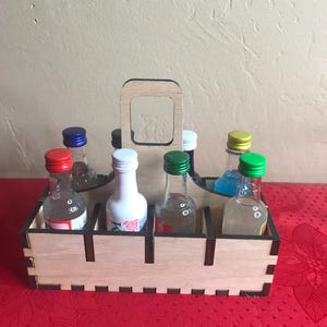 K&ouml;nnte beinhalten: Holz-Flaschenhalter mit Griff, der sechs kleine Glasflaschen mit bunten Kappen h&auml;lt. Die Flaschen sind in zwei Reihen zu je drei angeordnet. Der Halter ist aus hellem Holz mit dunkelbraunen Akzenten.