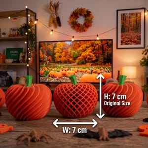 Könnte beinhalten: Drei orangefarbene Kürbisse mit grünen Stielen, bestehend aus zwei massiven Kürbissen mit Spiralmuster und einem zentralen Kürbis mit Gittermuster. Jeder Kürbis misst 7 cm in der Höhe und 7 cm in der Breite, wie durch den weißen Text angegeben.