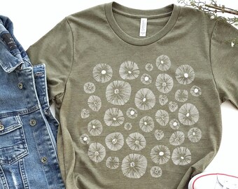 May include: An olive green short-sleeve t-shirt featuring a white graphic print of various circular mushroom cap patterns arranged in a cluster across the center of the chest, with a crew neckline and a standard fit.