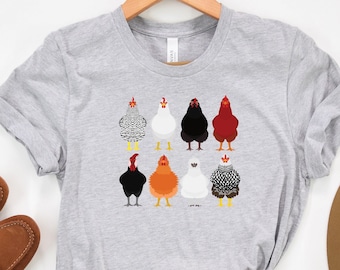 Może przedstawiać: Szary t-shirt z grafiką przedstawiającą osiem różnych kurczaków w różnych kolorach i wzorach. Kurczaki są odwrócone plecami do widza.