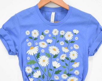 May include: A light blue t-shirt with a white daisy floral print. The daisies are arranged in a vertical pattern and have yellow centers.