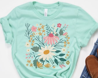 May include: A light blue t-shirt with a floral print featuring pink, yellow, and green flowers. The shirt is made of a soft, comfortable material.