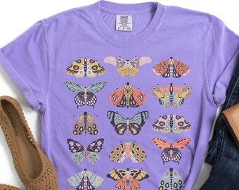 May include: A purple t-shirt with a graphic print of colorful butterflies. The shirt has a crew neck and short sleeves.