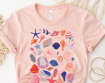May include: A pink t-shirt with a colorful pattern of seashells and starfish. The design is centered on the front of the shirt.