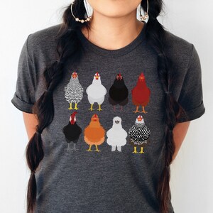 Puede incluir: Una camiseta gris oscuro jaspeada con un gr&aacute;fico de nueve pollos diferentes en varios colores y patrones.