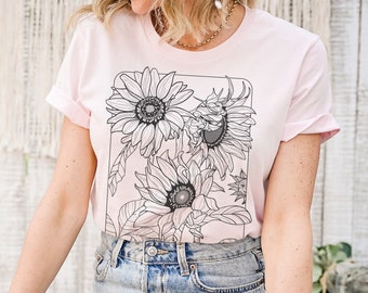 May include: A pink t-shirt with a black and white graphic of sunflowers. The graphic is in a rectangular frame.