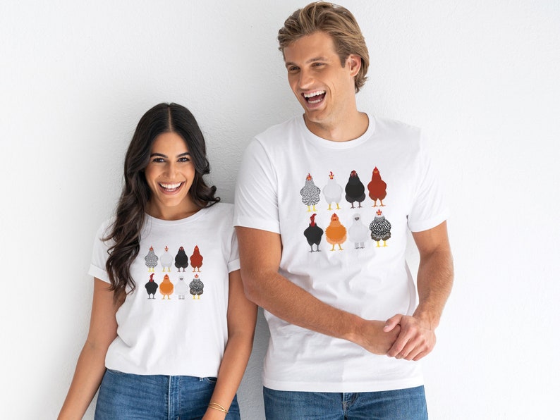 Puede incluir: Dos personas con camisetas blancas con un gr&aacute;fico colorido de pollos en la parte delantera. El gr&aacute;fico presenta nueve pollos en varios colores y patrones.