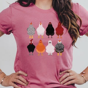 Puede incluir: Una camiseta rosa con un gr&aacute;fico de nueve pollos diferentes en varios colores y patrones. Los pollos est&aacute;n todos mirando hacia adelante y tienen las alas metidas.