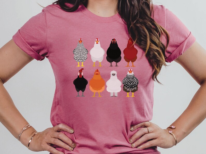 Puede incluir: Una camiseta rosa con un gr&aacute;fico de nueve pollos diferentes en varios colores y patrones. Los pollos est&aacute;n todos mirando hacia adelante y tienen las alas metidas.