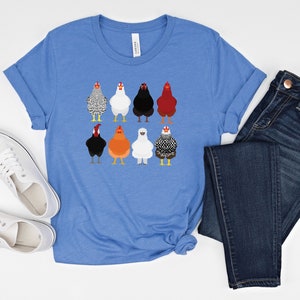 Puede incluir: Una camiseta azul con un gr&aacute;fico de nueve pollos diferentes. Los pollos son de diferentes colores y razas. La camiseta es de estilo casual con cuello redondo y mangas cortas.