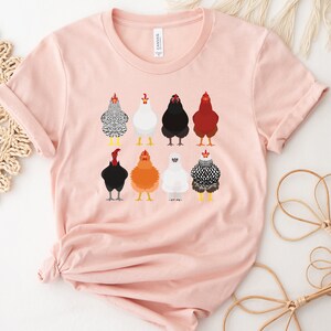 Puede incluir: Una camiseta rosa con un gr&aacute;fico de nueve pollos diferentes en varios colores y patrones. Los pollos est&aacute;n todos mirando hacia adelante y tienen las alas metidas.