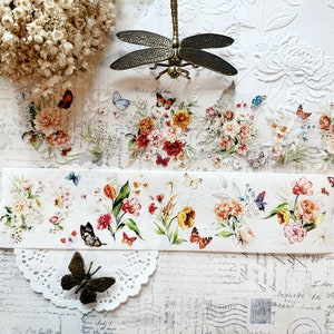 May include: A sheet of decorative washi tape with a floral design featuring pink, red, yellow, and white flowers, green leaves, and butterflies. The tape is on a white background with a dragonfly and a lace doily.