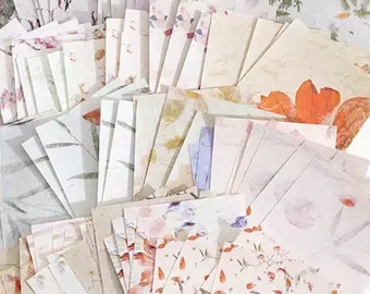Puede incluir: Una colección de cuadrados de papel decorativos con varios patrones florales en tonos de blanco, rosa y naranja. Los cuadrados de papel están dispuestos en forma de abanico, mostrando los diferentes diseños.