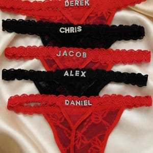Peut inclure: String en dentelle rouge et noire avec des noms en strass. Les noms "Derek", "Jacob" et "Daniel" sont sur des sous-v&ecirc;tements rouges, tandis que "Chris" et "Alex" sont sur des sous-v&ecirc;tements noirs. La lingerie a une bordure en dentelle d&eacute;licate.