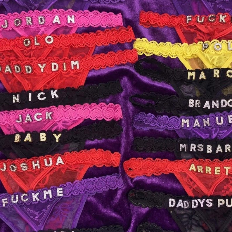 Peut inclure: Une collection de lingerie color&eacute;e, comprenant des strings et des bordures en dentelle assorties. La lingerie est de diff&eacute;rentes couleurs telles que le rose, le rouge, le noir, le violet et le jaune. Chaque pi&egrave;ce porte un nom ou un mot &eacute;pel&eacute; en lettres scintillantes.