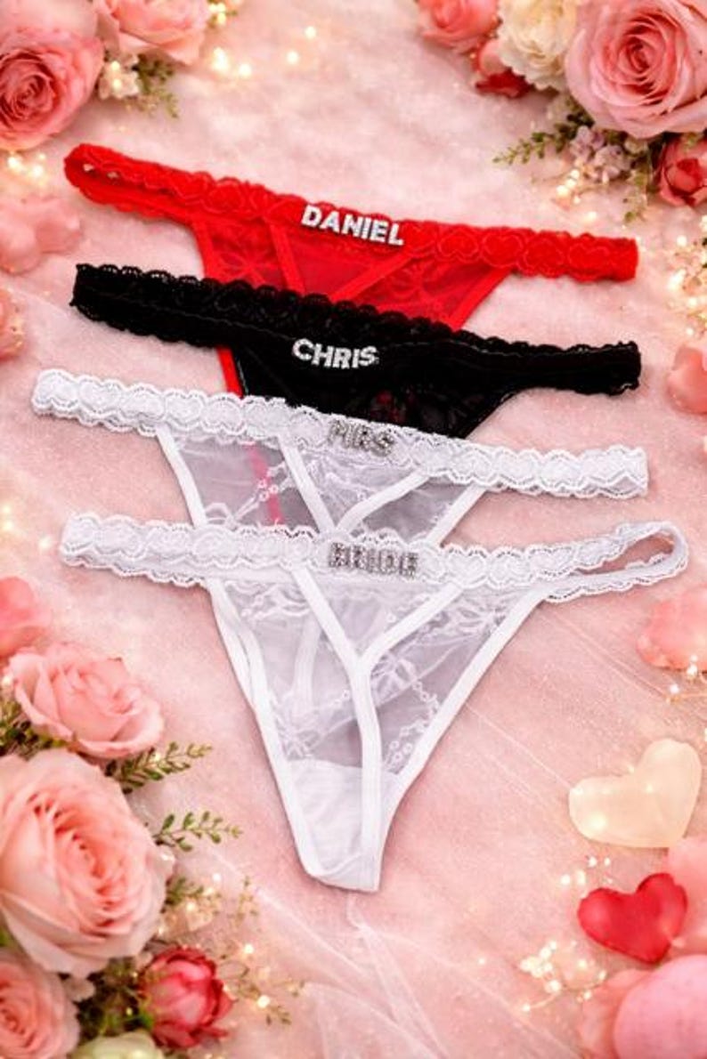 Peut inclure: Ensemble de strings rouges, noirs et blancs, orn&eacute;s de lettres en strass. Le string rouge porte l'inscription "DANIEL", le noir "CHRIS", et les blancs "MRS" et "BRIDE". La lingerie est pr&eacute;sent&eacute;e sur un fond rose avec des roses.