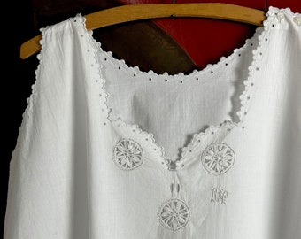 May include: White cotton sleeveless top with a scalloped neckline and embroidered floral details. The top has a small embroidered monogram "R.F." on the front.