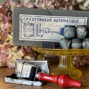 May include: Vintage wooden stamp set with a handle and a box labeled "Festonneur Automatique" in French. The stamps have various designs, including a zig-zag pattern and a floral design.
